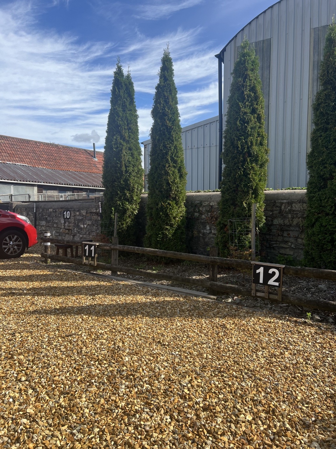 Numbered gravel parking bays 11 and 12 beside the fence